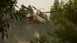 Helikopter Billings 4AJ mengisi ulang air untuk dijatuhkan ke Oak Fire dekat Mariposa, California, Amerika Serikat, 26 Juli 2022. Api membakar sebelah barat Taman Nasional Yosemite. (DAVID MCNEW/AFP)