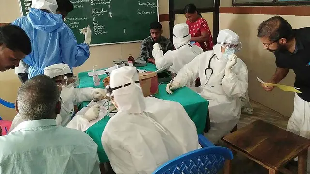 Petugas medis yang mengenakan pakaian pelindung sedang memeriksa pasien di rumah sakit Medical College di Kozhikode, India.