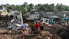 Warga Sri Lanka mengamati rumah mereka yang rusak tertimbun gundukan sampah yang longsor di Meetotamulla, dekat ibukota Kolombo, Minggu (16/4). Sedikitnya 23 orang tewas akibat tanah longsor di tempat pembuangan sampah tersebut. (ISHARA S. KODIKARA/AFP)