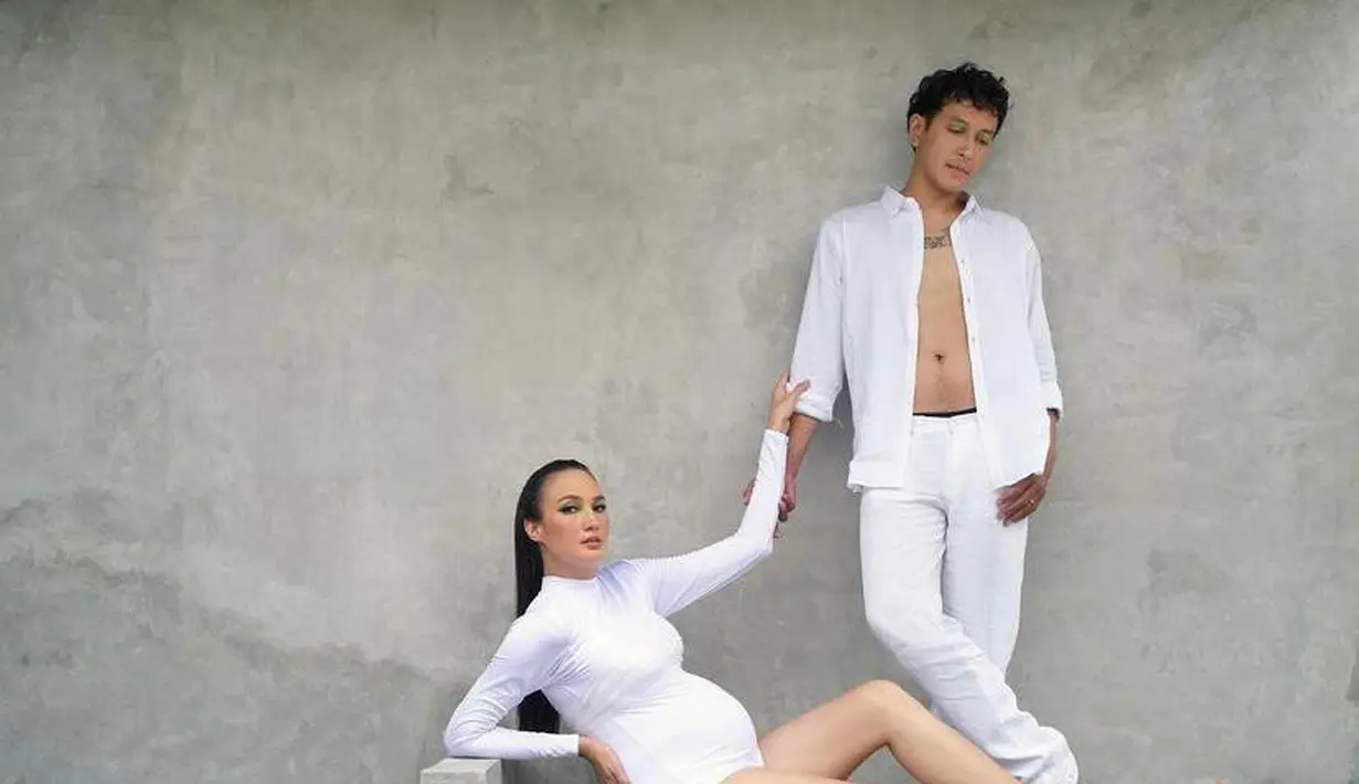 Foto pertama menampilkan Nadine dengan pose duduk, kaki terjulur lurus ke depan, dan Dimas berdiri dengan kemeja terbuka di sampingnya. Keduanya sama-sama mengenakan pakaian putih polos. Nadine memakai turtleneck lengan panjang dan bustier dari desainer Jacob William.