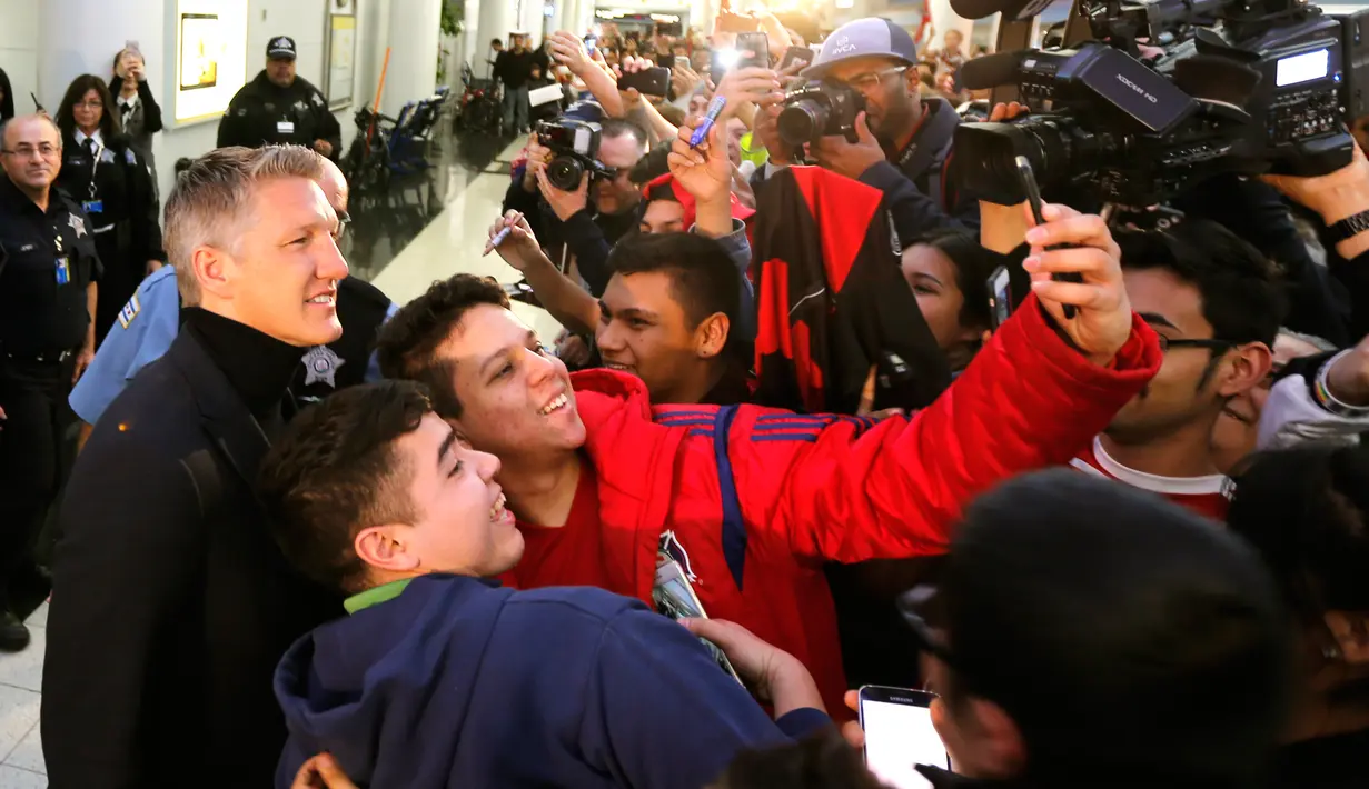 Pesepakbola Bastian Schweinsteiger berfoto bersama penggemar di Bandara Internasional O'Hare, Chicago, Selasa (28/3). Schweinsteiger bakal bergabung ke Fire di mana klub MLS itu mengeluarkan $4,5 juta untuk menggaetnya. (AP Photo/Charles Rex Arbogast)