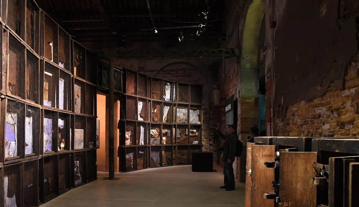 Pengunjung mengambil gambar karya seni berjudul 'A Straight Line Through the Carcass of History' buatan seniman Ghana Ibrahim Mahama saat pratinjau pers menjelang pembukaan pameran International Venice Biennale di Venesia, Italia, Rabu (8/5/2019). (TIZIANA FABI/AFP)