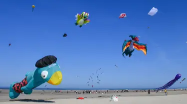 Orang-orang menerbangkan layang-layang berbagai bentuk dan warna dalam Festival Layang-Layang Internasional ke-32 di pantai Berck-sur-Mer, Prancis utara, 18 April 2018. Kegiatan internasional ini berlangsung hingga 22 April 2018. (Denis Charlet/AFP)