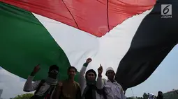 Peserta aksi membentangkan bendera Palestina di Lapangan Monumen Nasional, Jakarta, Jumat (11/5). Aksi ini untuk menyoroti konflik Palestina dan Israel pada perebutan bangunan suci atau Baitul Maqdis di kota Yerussalem. (Liputan6.com/Helmi Fithriansyah)