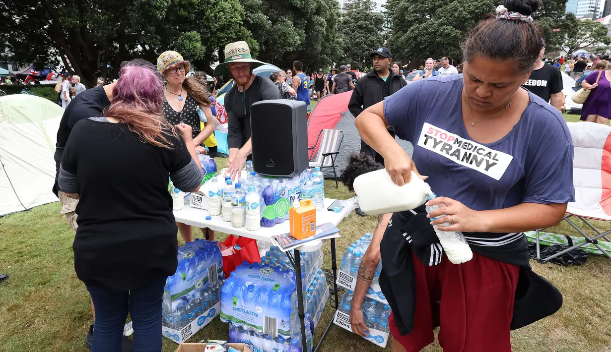 Relawan memasukkan susu ke dalam botol jika terjadi semprotan merica di halaman parlemen pada hari ketiga demonstrasi menentang pembatasan Covid-19, terinspirasi oleh demonstrasi serupa di Kanada, di Wellington (10/2/2022). (AFP/Marty Melville)