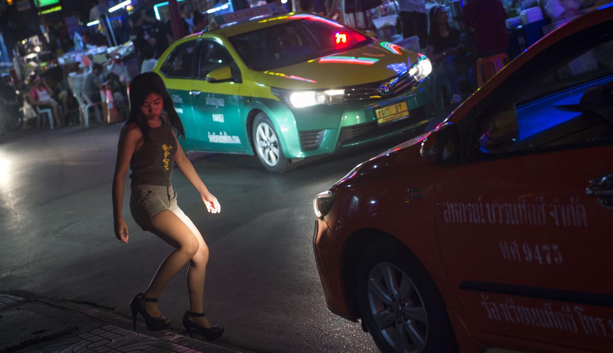 Foto pada 11 Oktober 2018 menunjukkan seorang wanita menyebrang jalan di Nana Red Light Distrik, Bangkok, Thailand. Nana Red Light District memang dikenal sebagai kawasan hiburan malam terbesar di Bangkok. (Romeo GACAD / AFP)