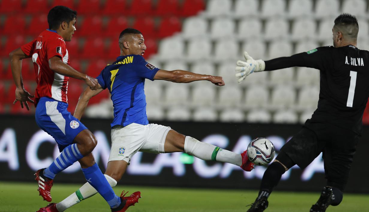 Striker Brasil, Richarlison (tengah) melepaskan tendangan yang coba di hadang kiper Paraguay, Antony Silva dalam laga kualifikasi Piala Dunia 2022 Zona Conmebol di Defensores del Chaco Stadium, Asuncion, Selasa (8/6/2021). Brasil menang 2-0 atas Paraguay. (AP/Jorge Saenz)