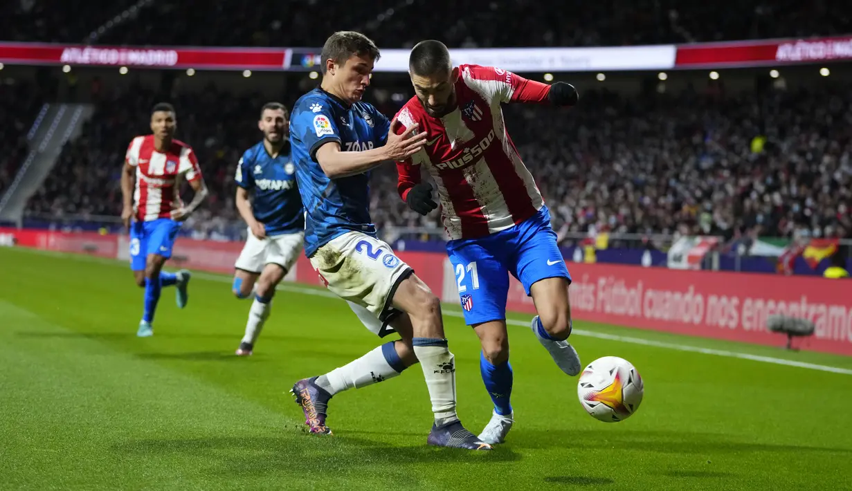 Gelandang Atletico Madrid Yannick Carrasco berebut bola dengan bek Deportivo Alaves Nahuel Tenaglia dalam lanjutan La Liga Spanyol, Minggu (3/4/2022) dinihari WIB. Atletico Madrid menang telak dengan skor 4-1 atas Deportivo. (AP Photo/Manu Fernandez)