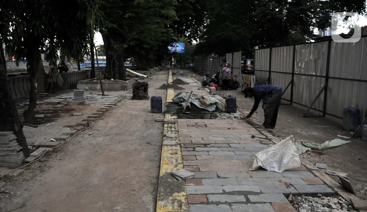 Pekerja Dinas SDA menyelesaikan proyek revitalisasi trotoar di Jalan RM Margono Djojohadikoesoemo, Jakarta, Kamis (16/1/2020). Trotoar di sisi selatan Kanal Banjir Barat itu akan dilengkapi taman dan deck view untuk melihat pemandangan Kali Ciliwung dan gedung perkantoran (merdeka.com/Iqbal Nugroho)