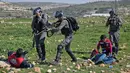 Petugas medis Palestina mengobati demonstran yang terlibat bentrokan saat tentara Israel menodongkan senjata ke rekannya di Ramallah, Tepi Barat, Senin (12/3). Aksi protes terkait pengangkapan salah satu mahasiswa oleh pasukan Israel. (AP/Nasser Nasser)