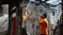 Petugas pemadam kebakaran melakukan proses pendinginan dengan menyemprotkan air ke puing bangunan untuk memastikan tidak ada titik api yang kembali menyala pascakebakaran di Jalan Kramat Pulo Dalam, Senen, Jakarta Pusat, Jumat (9/10/2026). (KLY/Budy Santoso)