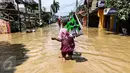 Pedagang alat kebersihan menerobos banjir di kompleks Pondok Gede Permai, Jatiasih, Bekasi, Jumat (22/4). Mereka menjajakan dagangannya berupa alat kebersihan ketika banjir di  kawasan tersebut mulai surut. (Liputan6.com/Fery Pradolo)