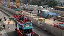 Seorang warga berlari menyambut Tontowi Ahmad, Liliyana Natsir, Eko Yuli dan Sri Wahyuni saat parade dengan bus Bandros menuju Istana Negara, Rabu (24/8/2016). (Bola.com/Nicklas Hanoatubun)