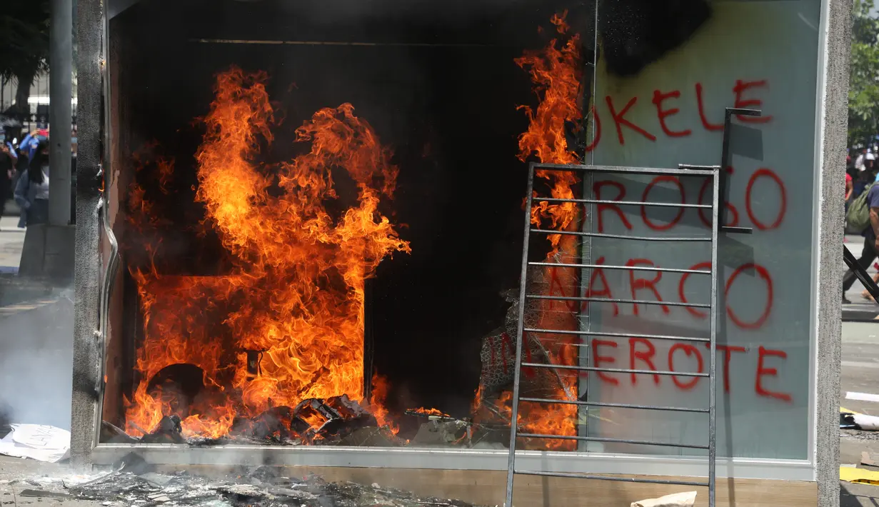 Mesin ATM bitcoin bernama Chivo terbakar selama protes terhadap kebijakan Presiden Nayib Bukele pada Hari Kemerdekaan di San Salvador, El Salvador, Rabu (15/9/2021). Ribuan warga Salvador berdemonstrasi menentang bitcoin, yang disahkan sebagai alat pembayaran oleh pemerintah. (MARVIN RECINOS/AFP)