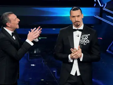 Striker AC Milan, Zlatan Ibrahimovic (kanan) dan presenter televisi Italia Amadeus tampil pada malam pembukaan festival musik San Remo di San Remo, Selasa (2/3/2021). Ibrahimovic yang sedang cedera melakukan debutnya sebagai pembawa acara di festival musik tersebut. (Marco RAVAGLI/AFP)