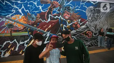 Warga berswafoto dengan latar belakang mural kolaborasi di Terowongan Kendal, Kawasan TOD Dukuh Atas, Jakarta, Rabu (6/7/2022). Disney Indonesia berkolaborasi bersama Jakarta Experience Board (JXB) dan Kita Art Friends menghadirkan karya seni mural terinspirasi dari film Marvel Studios "Thor: Love and Thunder." (Liputan6.com/Faizal Fanani)