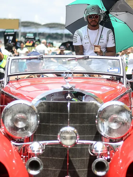 Pembalap Formula 1 Mercedes asal Inggris, Lewis Hamilton berpose di atas mobil Mercedes-Benz klasik saat mengikuti parade jelang Grand Prix Formula 1 Malaysia di Sirkuit Internasional Sepang, Malaysia, (2/10). (AFP PHOTO/Manan Vatsyayana)