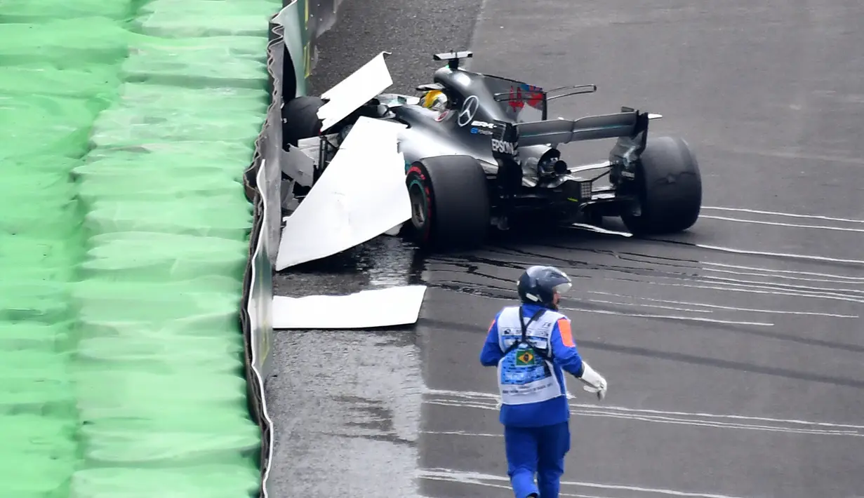 Pembalap Mercedes, Lewis Hamilton menabrak dinding pembatas lintasan saat kualifikasi F1 GP Brasil di sirkuit Interlagos di Sao Paulo, Brasil (11/11). Akibat Hamilton menabrak dinding sesi kualifikasi tertunda sejenak. (AFP Photo/Nelson Almeida)