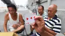 Sebuah kartu diperlihatkan saat bermain di trotoar di luar gedung apartemen di Beijing, China (10/8). Kartu ini sering juga digunakan untuk hal-hal lain, seperti sulap, enkripsi, permainan papan, dan pembuatan rumah kartu. (AFP Photo/Greg Baker)