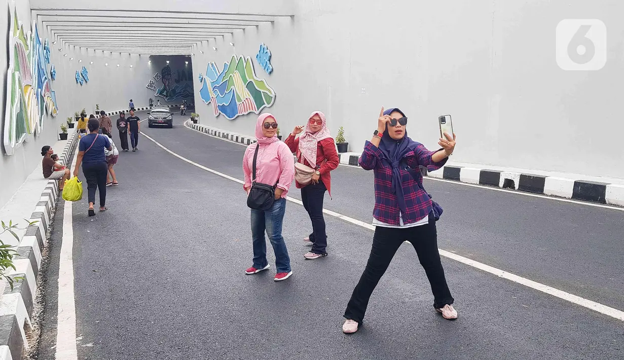 Sejumlah warga berfoto saat peresmian Jalan Underpass Dewi Sartika di Depok, Jawa Barat, Selasa (17/1/2023). Pekerjaan underpass Dewi Sartika ini membutuhkan waktu sekitar satu tahun atau mulai dikerjakan pada Februari 2022. (Liputan6.com/Herman Zakharia)