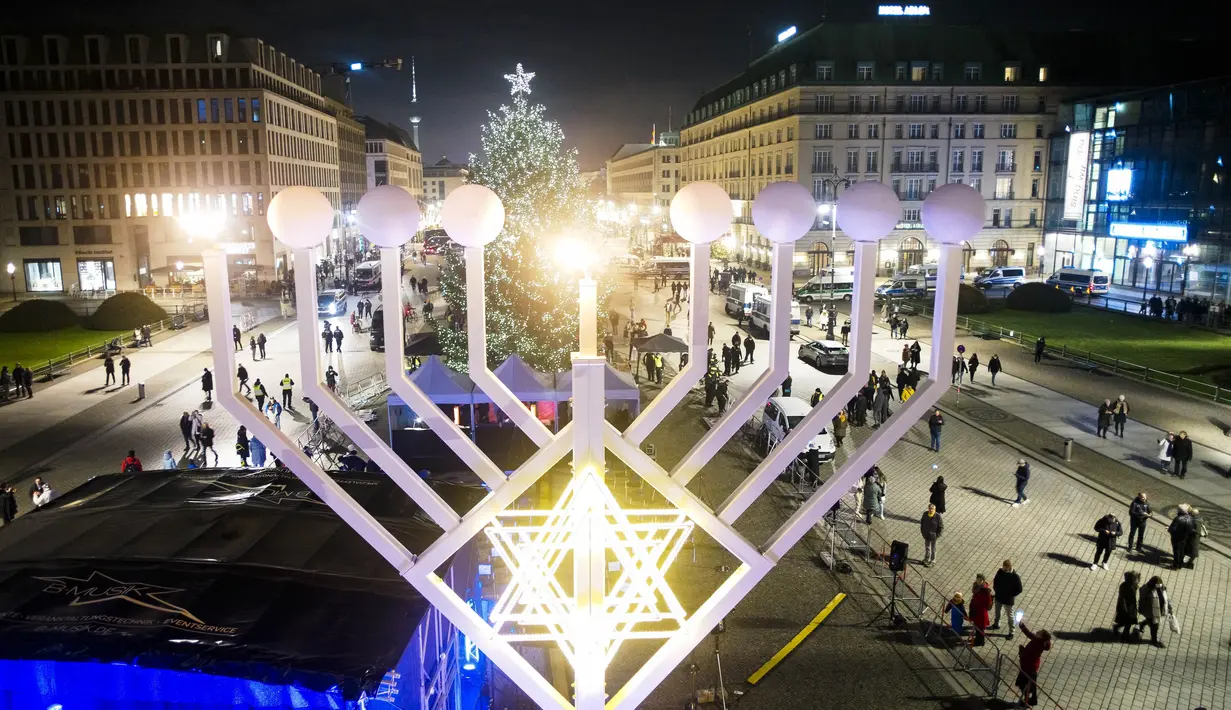 Hanukkah Menorah diterangi, menandai dimulainya Festival Cahaya Yahudi, di Pariser Platz dekat Gerbang Brandenburg di Berlin, Jerman, Minggu (28/11/2021). Orang Yahudi di seluruh dunia akan merayakan Hanukkah hingga 6 Desember. (AP Photo/Markus Schreiber)