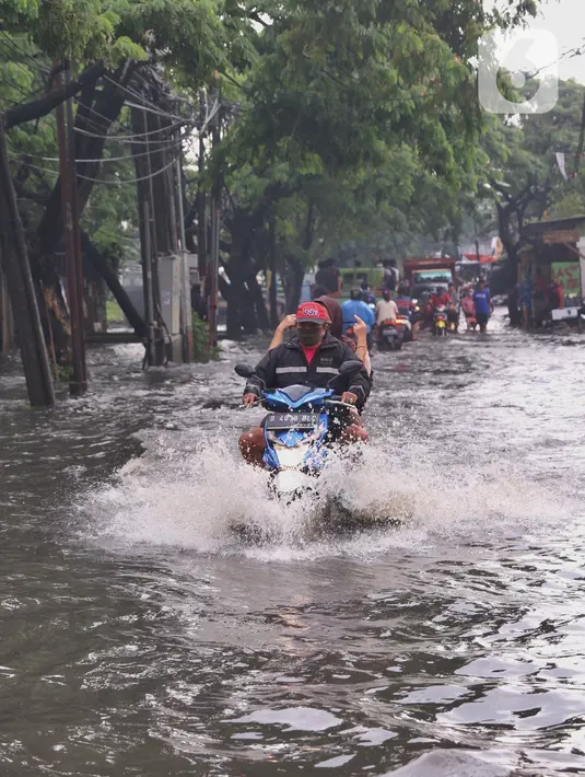 Pengendara motor menerjang banjir di Jalan KH. Ahmad Dahlan Cipondoh, Tangerang, Selasa (16/2/2021). Hujan deras yang melanda wilayah Tangerang mengakibatkan ruas jalan alternatif penghubung Tangerang dengan Jakarta tersebut banjir setinggi lutut orang dewasa. (Liputan6.com/Angga Yuniar)