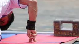 Seorang pria menunjukkan kemampuann push up dengan dua jari pada kompetisi seni bela diri '72 Arts of Shaolin' di kuil Shaolin, Provinsi Henan, China, 30 Juli 2017. Kompetisi ini menampilkan para jago kungfu yang memamerkan kekuatan fisik. (STR AFP)