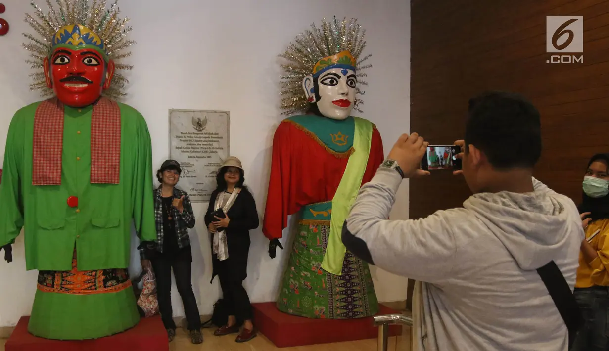 Pengunjung berpose di samping ondel-ondel yang ada di Museum Fatahillah dan Museum Wayang, Kota Tua, Jakarta, Selasa (26/6). Pemprov DKI menggratiskan biaya masuk sejumlah museum pada hari ini. (Liputan6.com/Arya Manggala)
