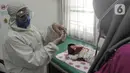 Dokter dengan Alat Pelindung Diri menunjukkan vaksin polio pada ibu di Rumah Vaksinasi Sawangan, Depok, Selasa (16/6/2020). Orang tua diminta tidak menunda pemberian imunisasi pada anak-anak yang masih harus menerima imunisasi lengkap, meskipun Covid-19 belum berakhir. (merdeka.com/Arie Basuki)