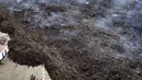 Petugas pemadam kebakaran berdiri di samping lahar yang mengalir saat gunung berapi terus meletus di pulau Canary La Palma, Spanyol, Senin (29/11/2021). Punggung bukit dan mengancam akan memperluas dampak pada tanah yang dievakuasi, infrastruktur dan rumah. (AP/Emilio Morenatti)