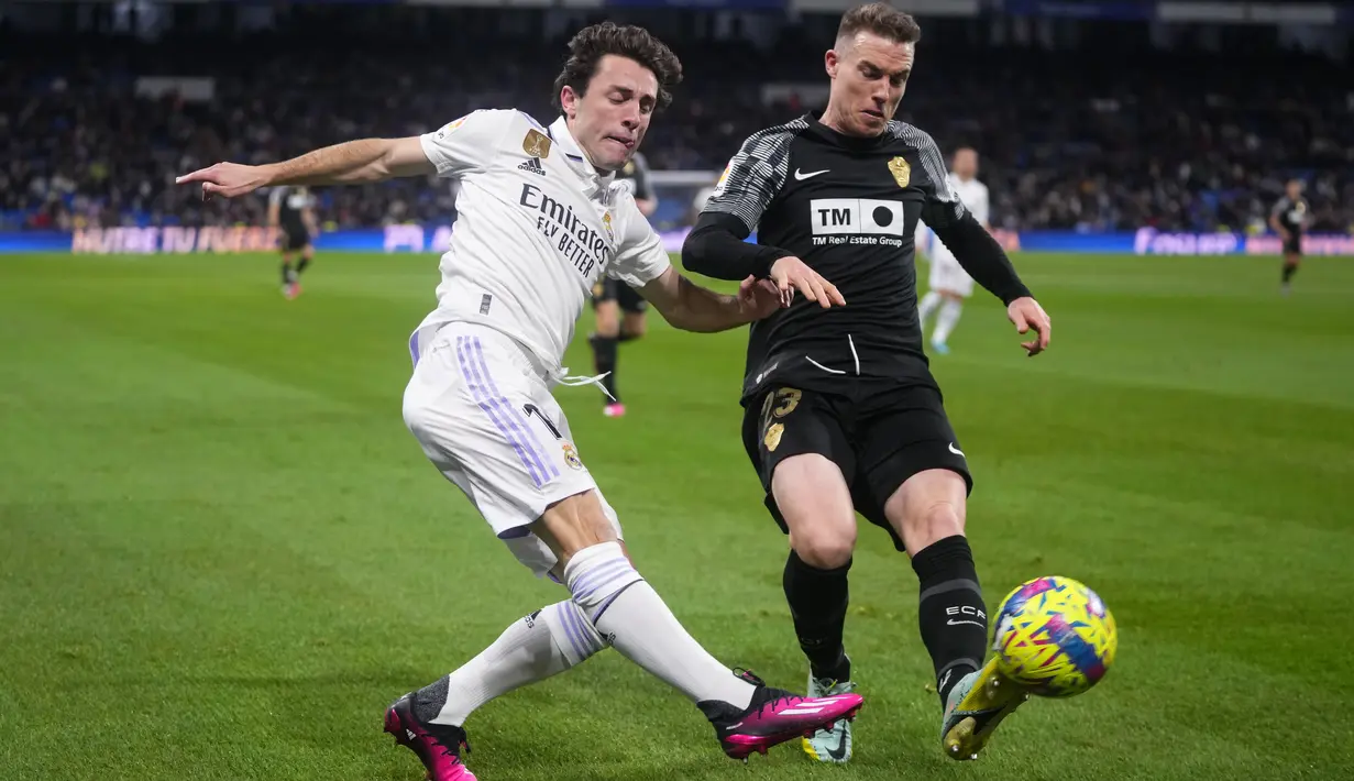 <p>Gelandang Real Madrid, Alvaro Odriozola berusaha mengumpan bola dari kawalan pemain Elche, Carlos Clerc selama pertandingan lanjutan La Liga Spanyol di stadion Santiago Bernabeu di Madrid, Spanyol, Kamis (16/2/2023). Pasukan Carlo Ancelotti ini kini menempati urutan kedua dengan margin 8 poin di bawah sang pemuncak, Barcelona. (AP Photo/Manu Fernandez)</p>