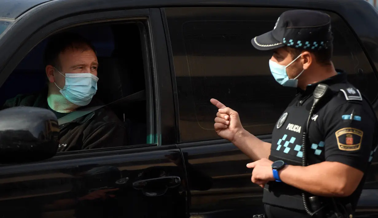 Petugas polisi setempat mengontrol pergerakan orang di sebuah pos pemeriksaan lalu lintas di kota Fuenlabrada yang tertutup sebagian, di wilayah Madrid (22/9/2020). Penguncian dilakukan akibat infeksi virus melonjak. (AFP/Oscar Del Pozo)