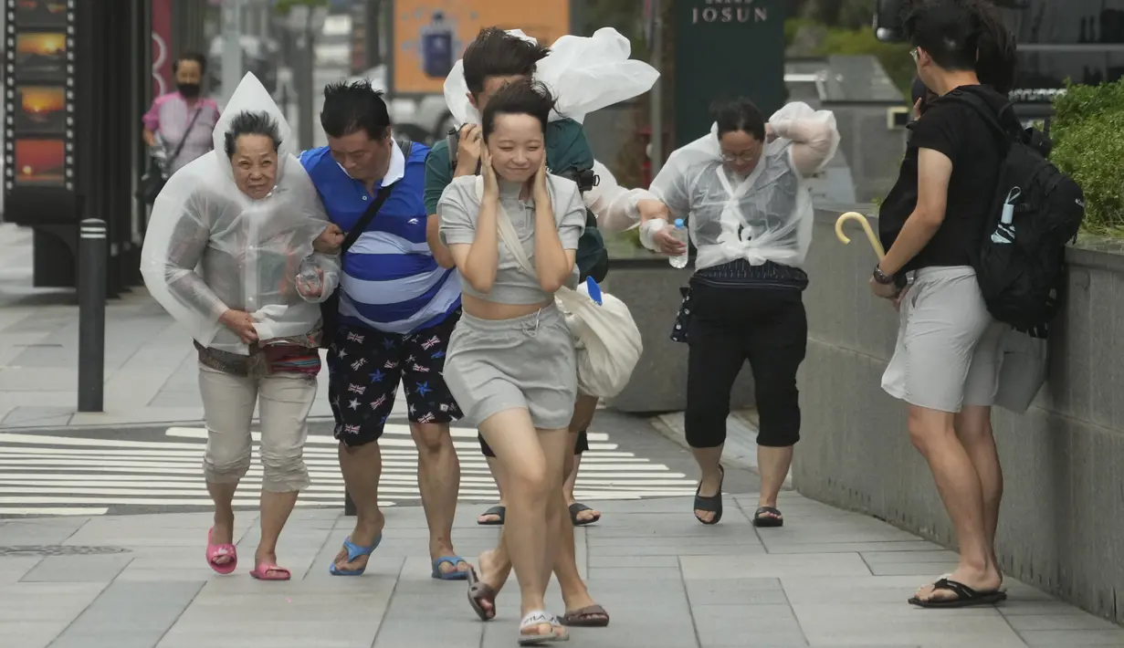 Orang-orang berjuang di tengah hujan dan angin saat badai tropis bernama Khanun mendekat ke Semenanjung Korea, di Busan, Kamis, 10 Agustus 2023. (AP Photo/Ahn Young-joon)