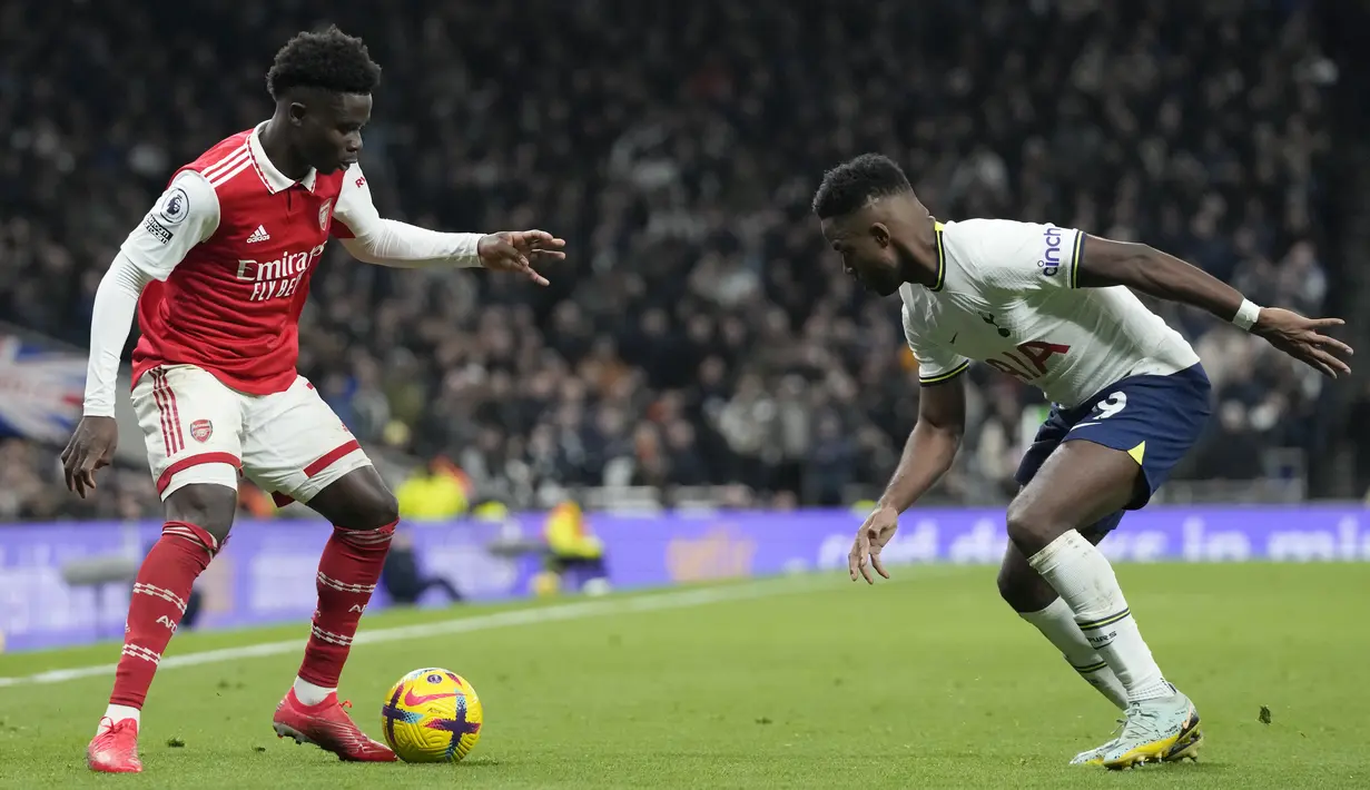 <p>Pemain Arsenal, Bukayo Saka berusaha melewati pemain Tottenham Hotspur, Ryan Sessegnon pada pertandingan lanjutan Liga Inggris di Stadion Tottenham Hotspur di London, Inggris, Minggu (15/1/2023). Hasil ini membuat Arsenal makin kokoh di puncak klasemen dengan koleksi 47 angka dari 18 laga. (AP Photo/Frank Augstein)</p>