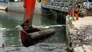 Petugas mengangkat batang pohon dari Kali Sekretaris menggunakan alat berat, Jakarta, Rabu (1/11). Kegiatan ini rutin di lakukan oleh Pasukan Oranye guna mengantisipasi banjir di wilayah Ibukota. (Liputan6.com/Johan Tallo)
