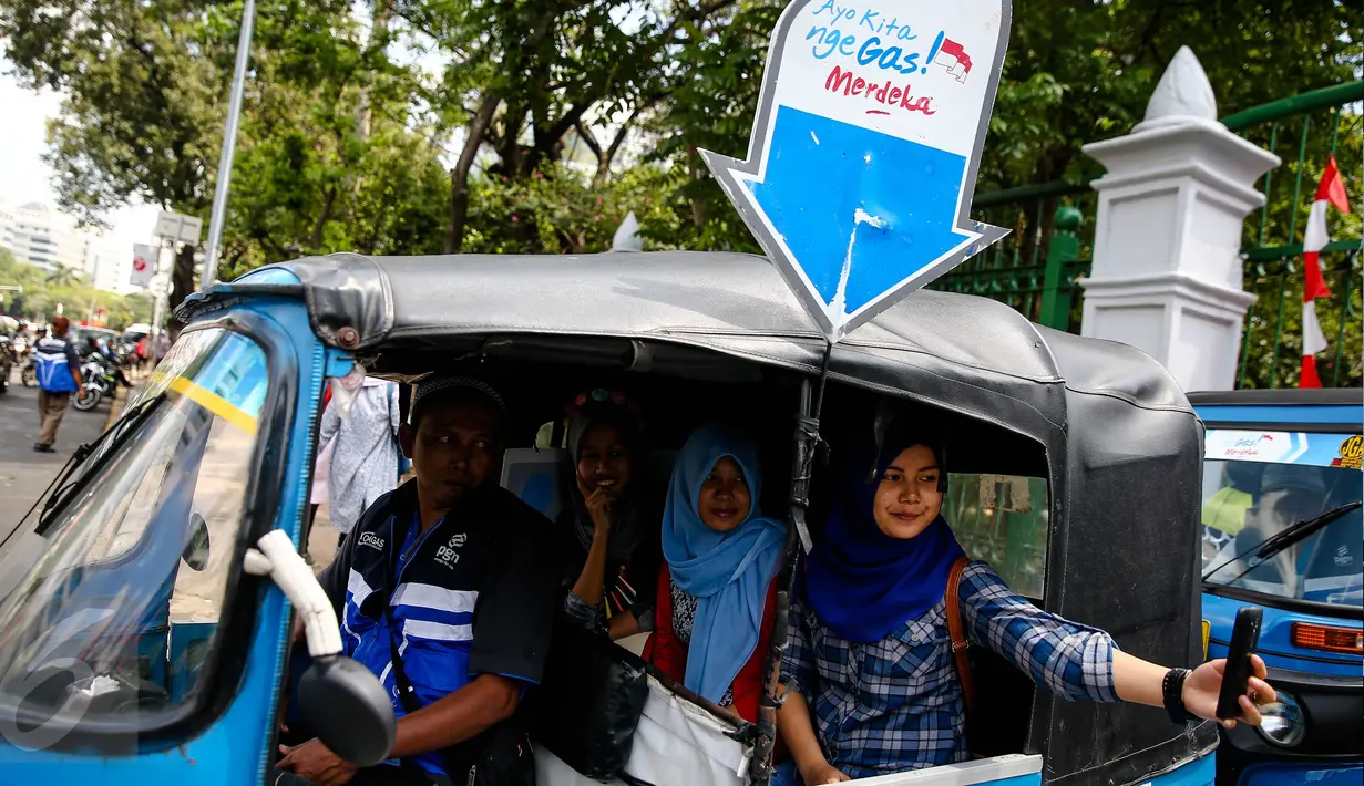Warga berselfie diatas bajaj bahan bakar gas (BBG) gratis dikawasan Monas Jakarta, Rabu (17/8). Program bajaj gas gratis ini akan berlangsung mulai tanggal 14-20 Agustus 2016. (Liputan6.com/Faizal Fanani)