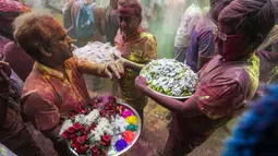 Umat Hindu dengan persembahan berjalan menuju mobil yang membawa patung dewa Krishna selama festival Holi di Kolkata, India, Minggu, 5 Maret 2023. Holi merupakan selebrasi adat umat Hindu India yang menjadi festival paling dinanti para pelancong mancanegara ketika berkunjung ke India. .(AP Photo/Bikas Das)