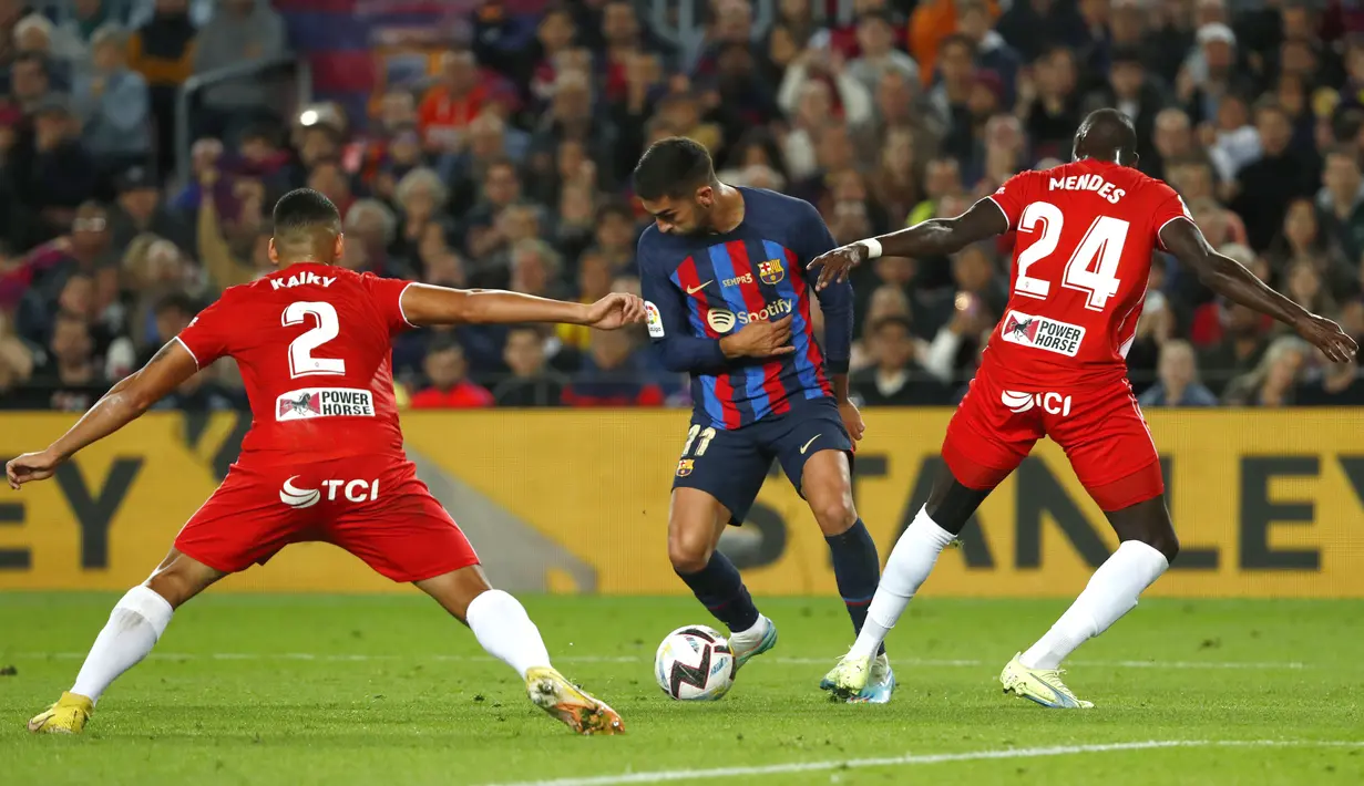Penyerang Barcelona, Ferran Torres mengontrol bola dari kawalan pemain Almeria, Kaiky dan Houboulang Mendes selama pertandingan lanjutan La Liga Spanyol di stadion Camp Nou di Barcelona, Spanyol, Minggu (6/11/2022). Barcelona menang atas Almeria dengan skor 2-0. (AP Photo/Joan Monfort)