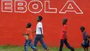 Sejumlah anak berjalan melewati dinding yang bertuliskan 'Ebola' di Monrovia, Liberia, 31 Agustus 2014. Liberia melarang para awak kapal untuk berlabuh di negara-negara yang rentan epidemi Ebola. (AFP PHOTO/DOMINIQUE FAGET)