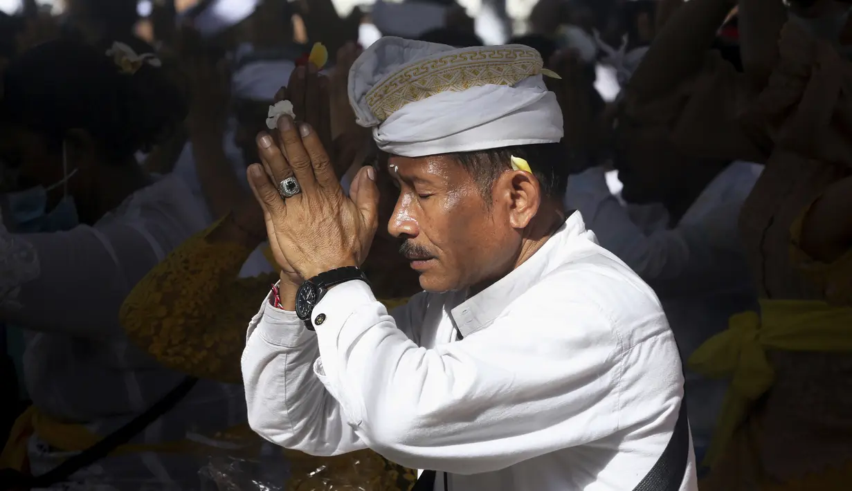 Seorang pria berdoa saat merayakan Hari Raya Kuningan di Pura Sakenan, Bali, Sabtu (18/6/2022). Kuningan menandai hari terakhir perayaan Galungan, salah satu upacara keagamaan terbesar umat Hindu di Bali. (AP Photo/Firdia Lisnawati)