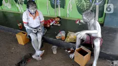 Seorang ibu menghitung uang hasil mengamennya sebagai "Manusia Silver " bersama sang anak di salah satu sudut toko di kawasan perempatan Gaplek, Pamulang, Tangerang Selatan, Sabtu (16/1/2021). Ibu tersebut mendapat penghasilan sekitar 50 ribu per hari sebagai Manusia Silver (merdeka.com/Arie Basuki)