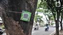 Warga memindai "QR code" yang terpasang pada salah satu pohon di Jalan Ir H Juanda, Depok, Jawa Barat, Minggu (27/11/2022). Pemerintah Kota Depok memasang "QR code" pada 1.500 pohon perindang di Jalan Margonda Raya dan Jalan Ir H Juanda dengan total anggaran Rp49 juta untuk mengedukasi warga dengan informasi berupa nama pohon, nama ilmiah, umur maksimal, tinggi, lokasi, daya serap CO2 dan kode pohon untuk pendataan. (merdeka.com/Iqbal S. Nugroho)
