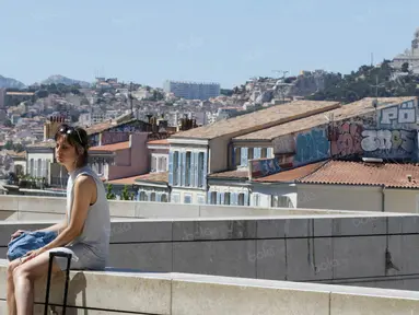 Seorang wanita duduk dengan latar belakang suasana kota di Marseille, Prancis, Minggu (3/7/2016). Marseille merupakan daerah pesisir di selatan Prancis dengan pesona keindahan alam. (Bola.com/Vitalis Yogi Trisna)