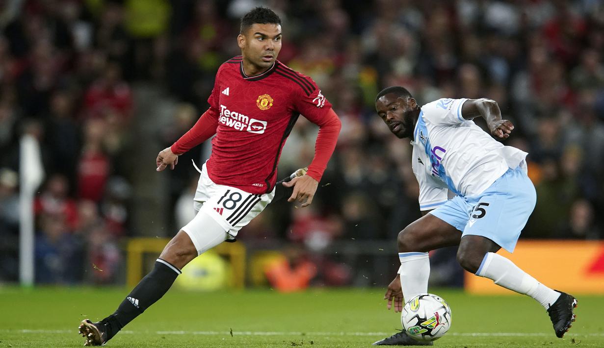 Pemain Manchester United, Casemiro (kiri) menggiring bola melewati pemain Crystal Palace, Jeffrey Schlupp pada laga putaran ketiga Carabao Cup 2023/2024 di Old Trafford, Manchester, Inggris, Rabu (27/09/2023). Casemiro juga sukses membuat assist untuk gol Anthony Martial pada babak kedua. (AP Photo/Dave Thompson)