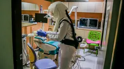 Dr. Maureen P. Ines-Manzano, seorang dokter gigi, mengenakan setelan respirator dengan pemurni udara di dalam kliniknya di Manila, Filipina, pada 19 Oktober 2020. Pasien Dr. Manzano menjulukinya "dokter gigi astronaut" karena mengenakan setelan PAPR utuk menghindari COVID-19. (Xinhua/Rouelle Umali)