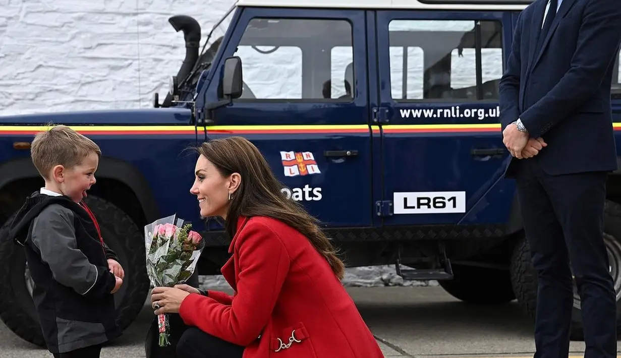 Kate Middleton mendapat bunga dari seorang bocah menjadi momen menyentuh. Ia menerima bunga tersebut dengan mengenakan long coat merah. [instagram/princeandprincessofwales]