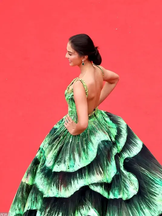 Beginilah gaya Raline Shah saat hadiri acara bergengsi dunia di red carpet Cannes 2022, Prancis. Tampak rambut yang disanggul memamerkan bahu dan punggungnya. Ia memakai gaun hijau glow in the dark rancangan Michael Cinco.