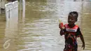 Seorang anak bermain di tengah jalan permukiman Bukit Duri, Jakarta yang terendam banjir, Kamis (16/2). Meluapnya Bendungan Katulampa, Bogor, menyebabkan permukiman kawasan Bukit Duri tergenang air dengan ketinggian 10 - 80 cm. (Liputan6.com/Helmi Afandi)