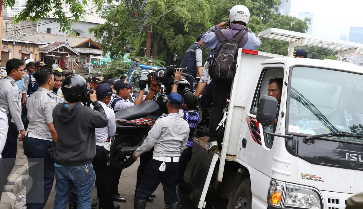 Petugas Dishub mengangkut motor ke atas truk saat razia parkir liar di kawasan Tanah Abang, Jakarta, Senin (14/11). Meski sudah ditertibkan, pengendara masih tak menghiraukan peraturan tersebut yang mengakibatkan kemacetan. (Liputan6.com/Gempur M Surya)
