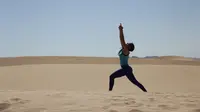 Seorang wanita mengikuti kelas yoga yang digelar di gurun Samalayuca, negara bagian Chihuahua, Meksiko, 28 April 2018. Ratusan penggemar yoga mengikuti latihan bersama di bawah terik matahari dan beralaskan pasir. (AFP PHOTO / HERIKA MARTINEZ)